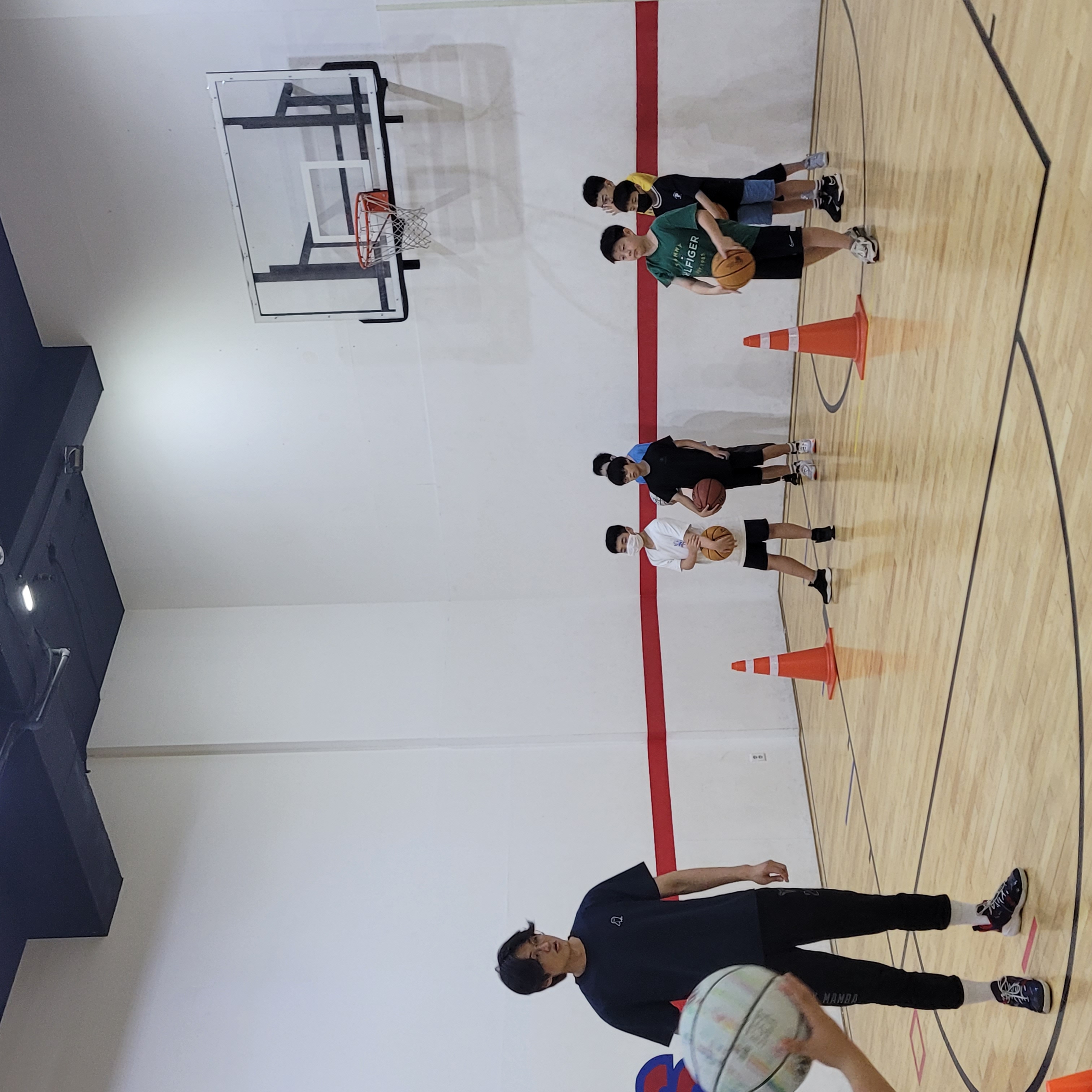 코치와 함께 드리블 연습을 하는 젊은 농구 선수들