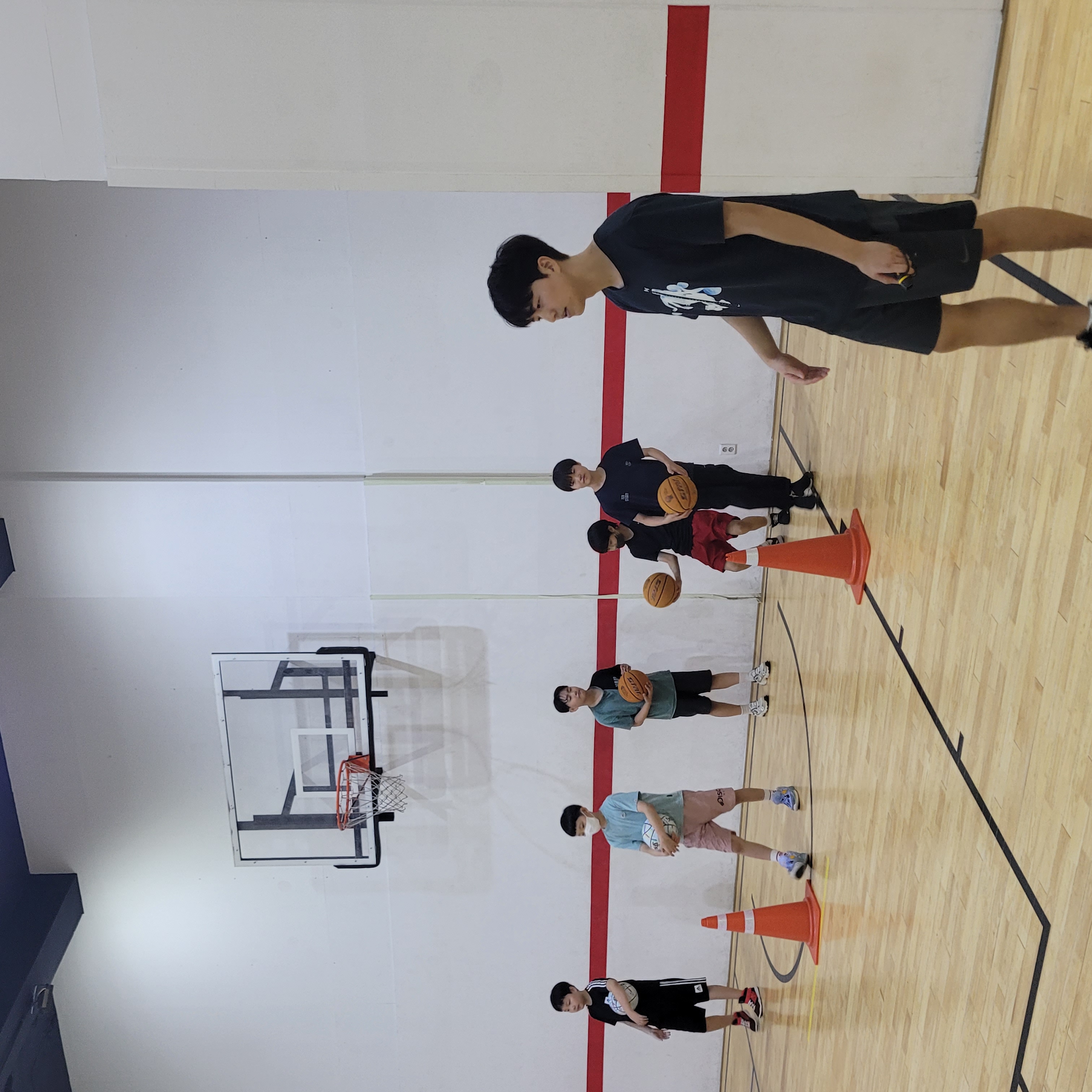 청소년 선수들과 함께 농구 드릴을 이끄는 코치